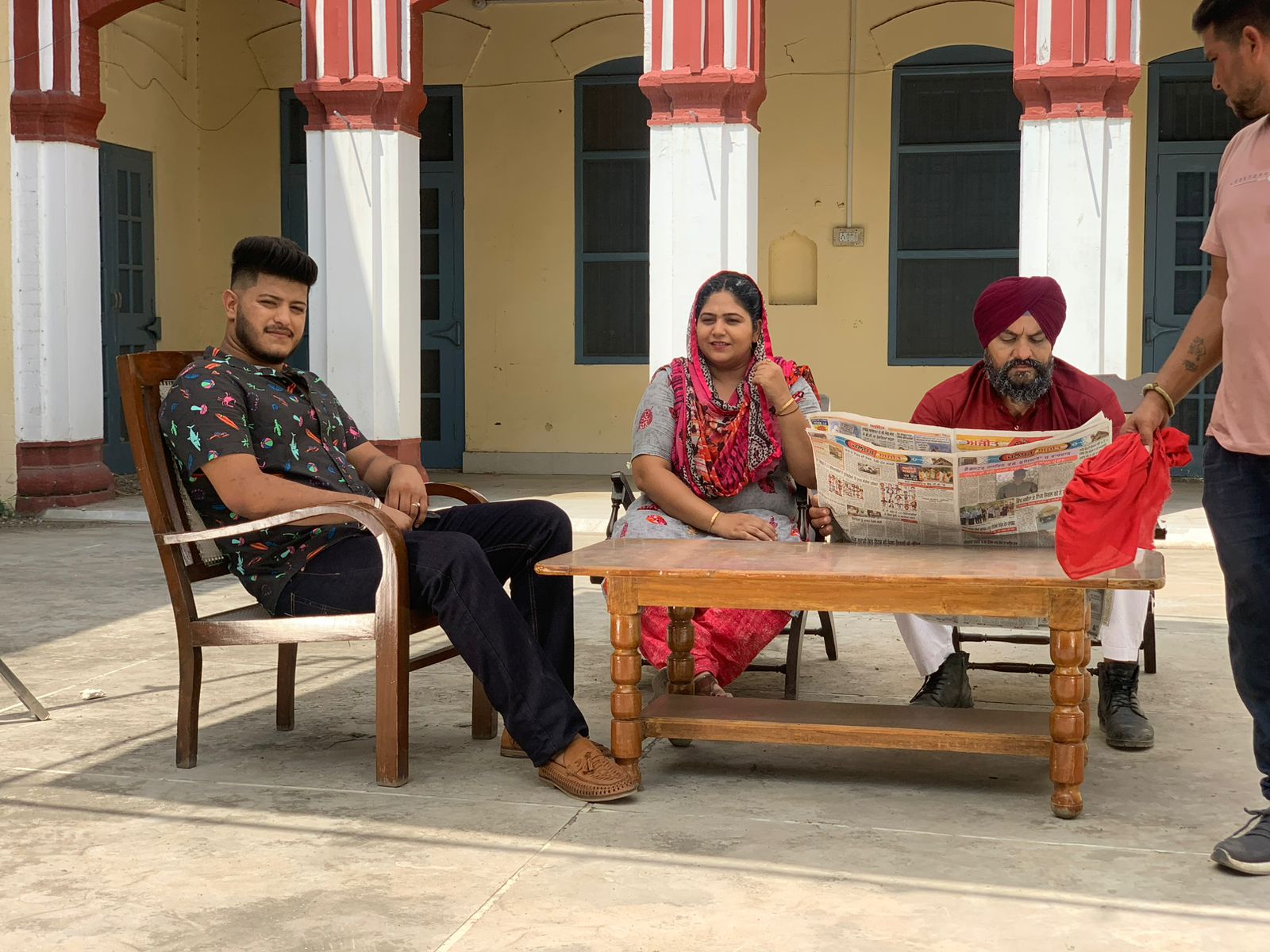 Music video scene with artists in traditional and modern Punjabi attire in a courtyard setting